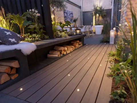 Recessed lights along a deck with built-in seating and surrounding plants